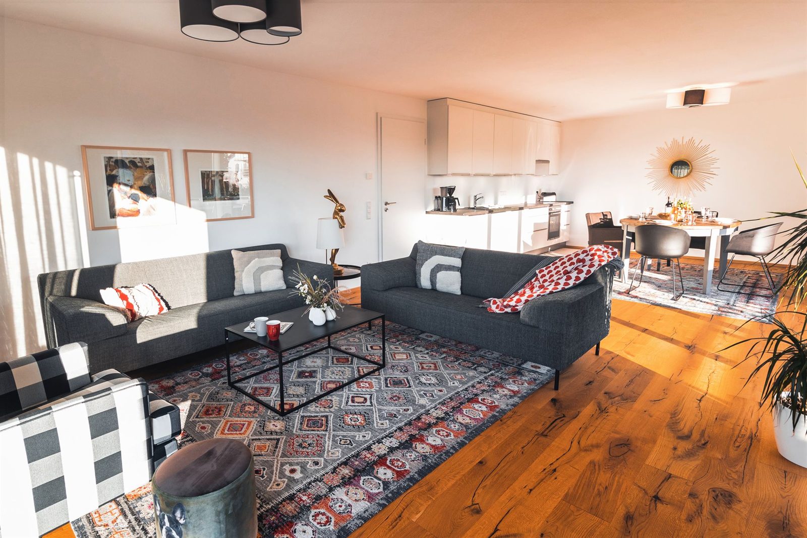 Wohnraum · Zwei Sofas vor der offenen Küche, rechts der runde Esstisch