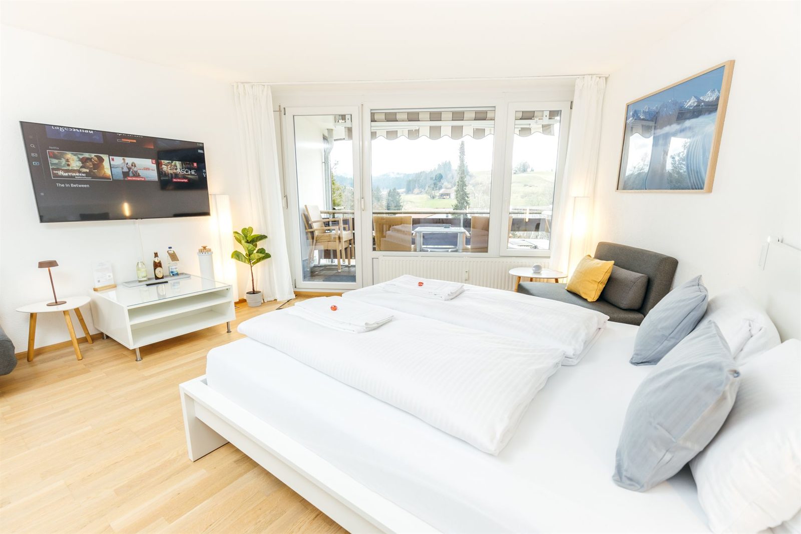 Studio · Doppelbett mit Smart-TV gegenüber, dahinter die Tür auf den Balkon