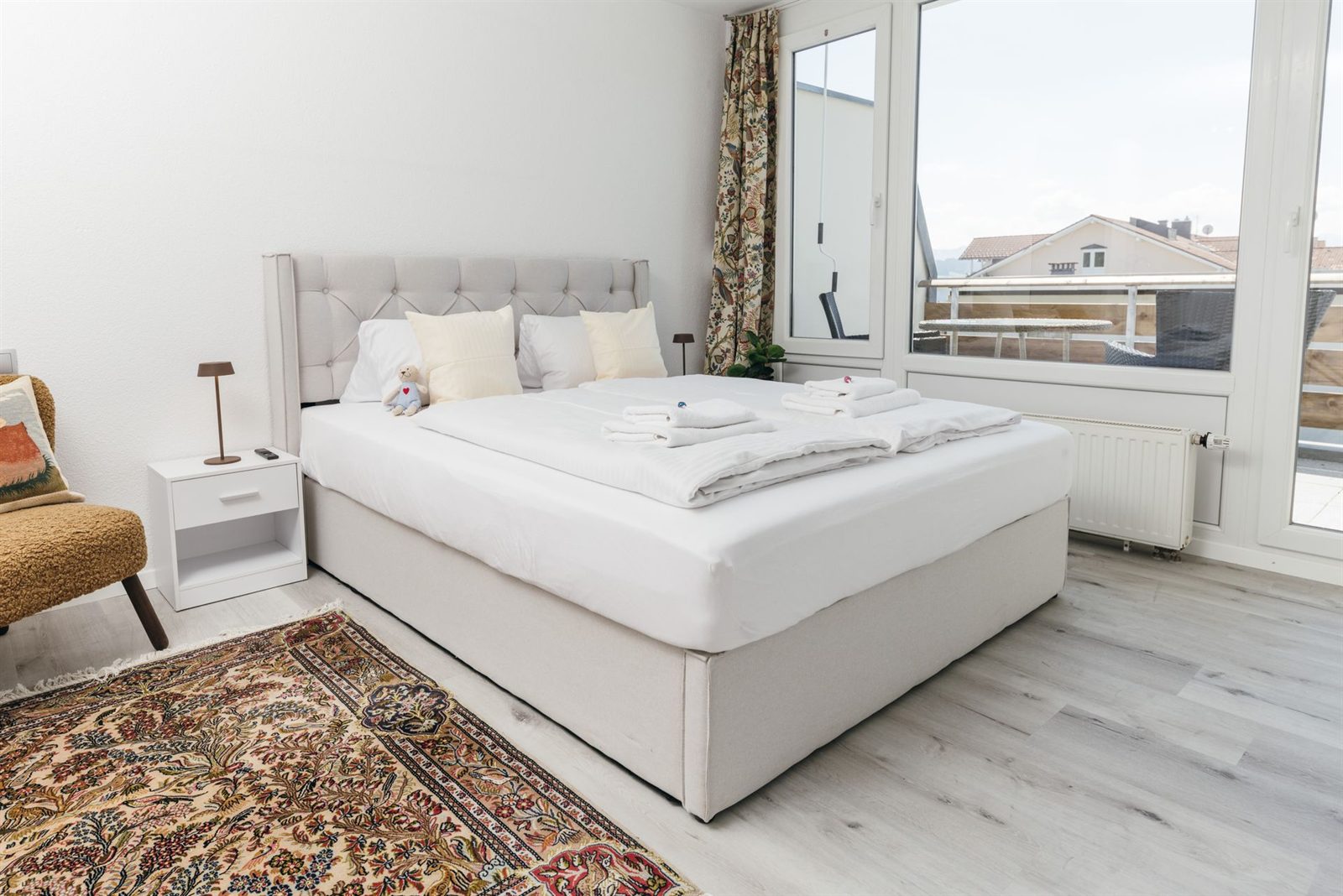 Schlafbereich · Boxspringbett mit gepolstertem Kopfteil und Nachttisch, daneben der Sessel
