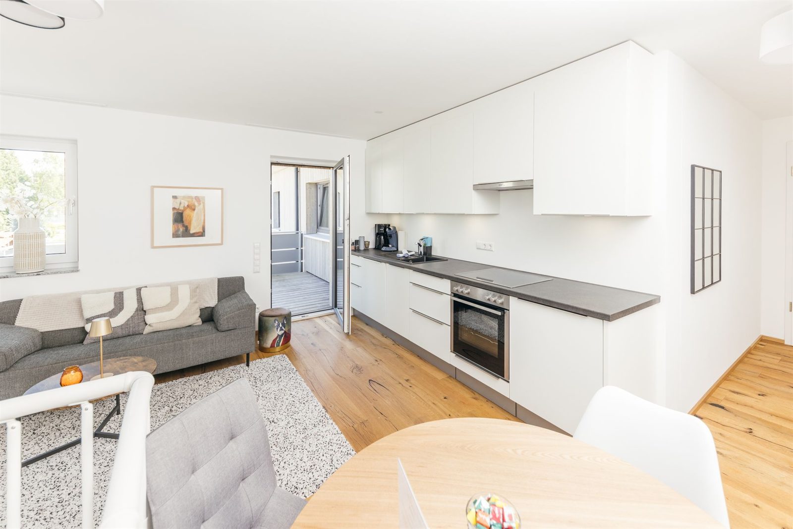 Wohnraum · Küchenzeile mit Backofen, Ceranfeld und Spüle, daneben Sofa und Esstisch