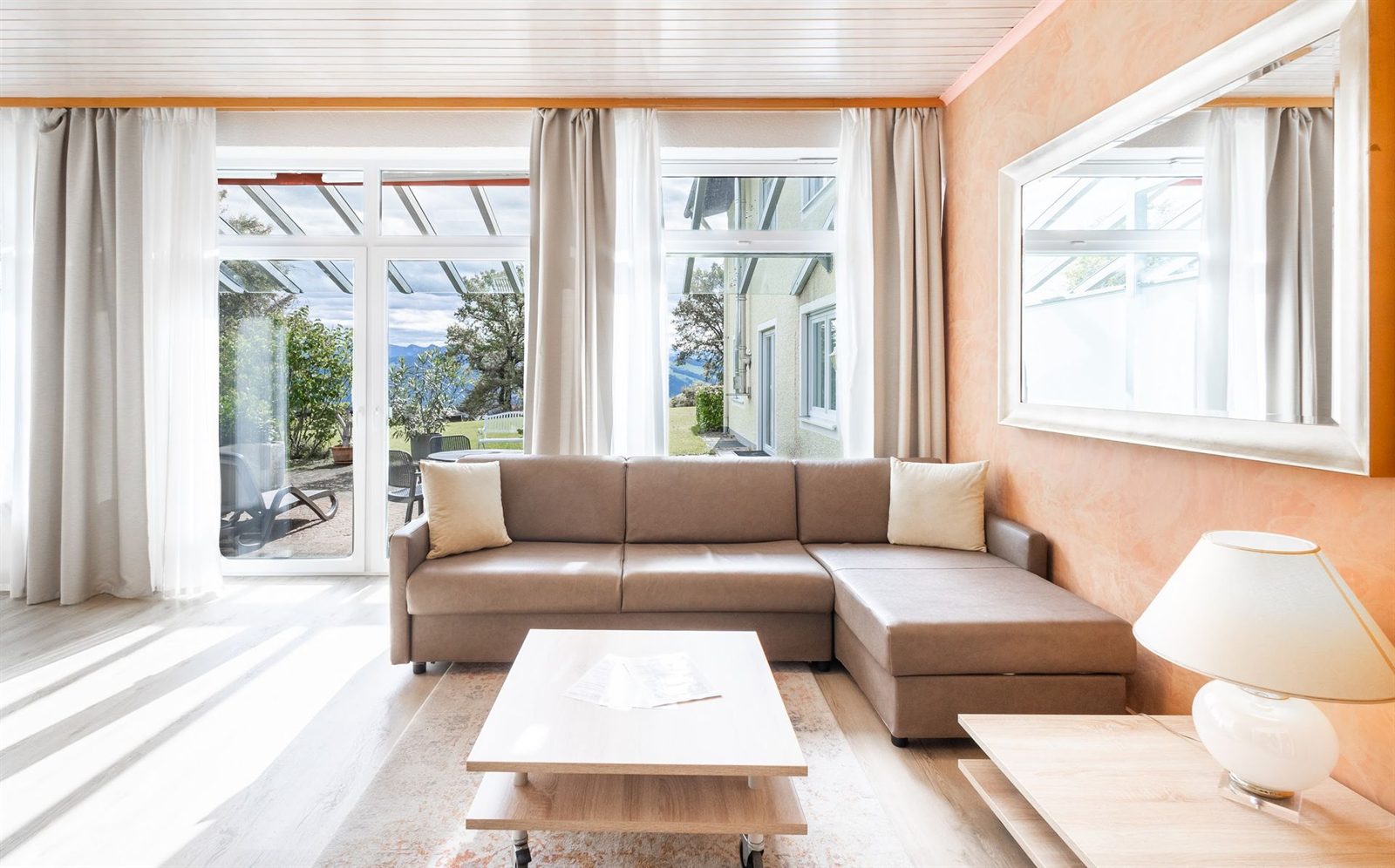 Wohnzimmer · Vom Ecksofa aus geht der Blick über die Terrasse bis zu den Bergen