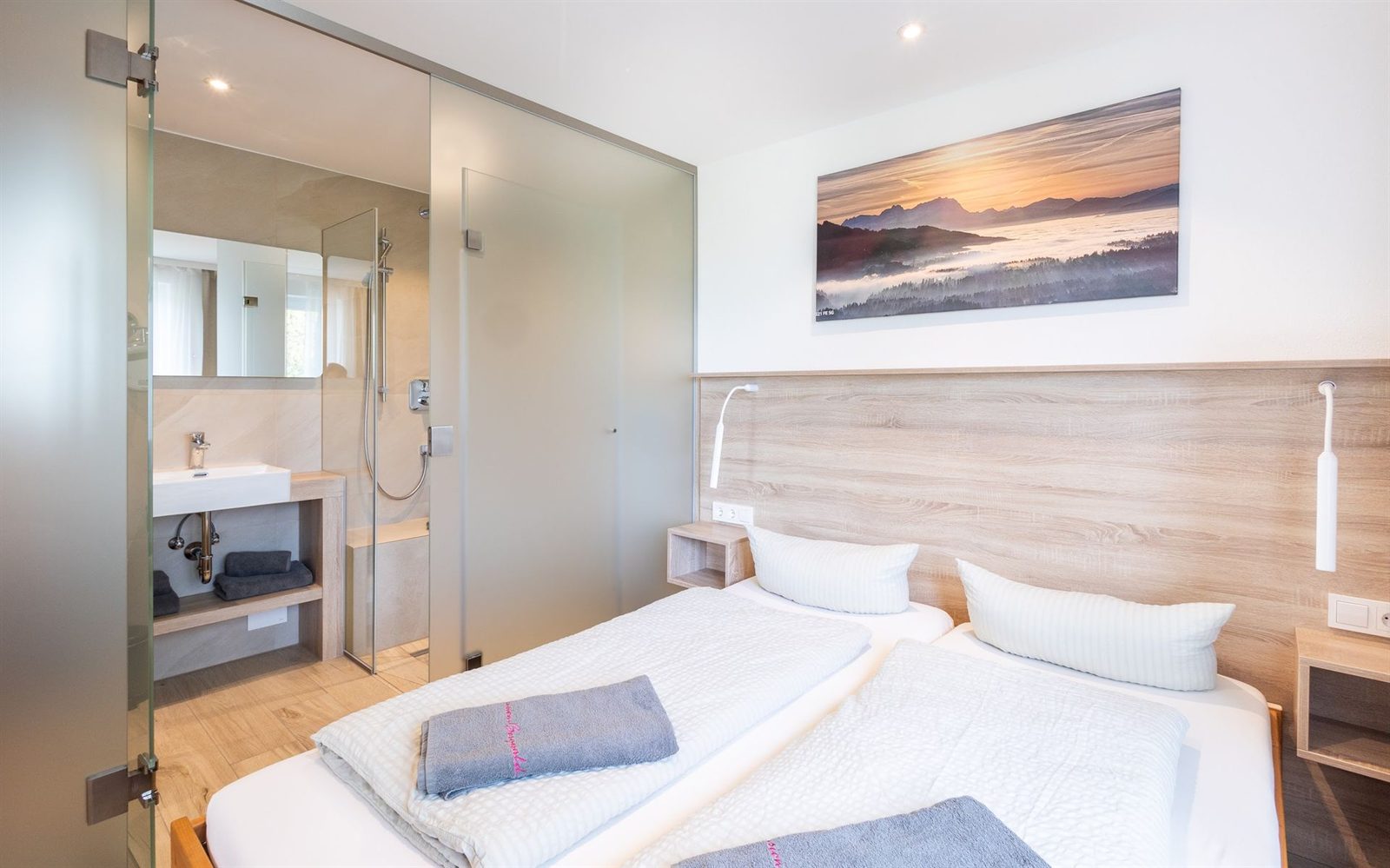 Schlafzimmer · Doppelbett mit Leseleuchten, dahinter liegt das Bad hinter Milchglas