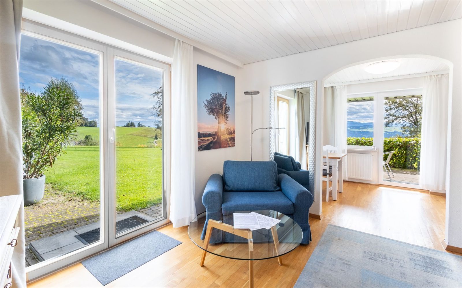 Wohnzimmer · Zwei Türen führen ins Freie — eine zur Wiese, eine zur überdachten Terrasse