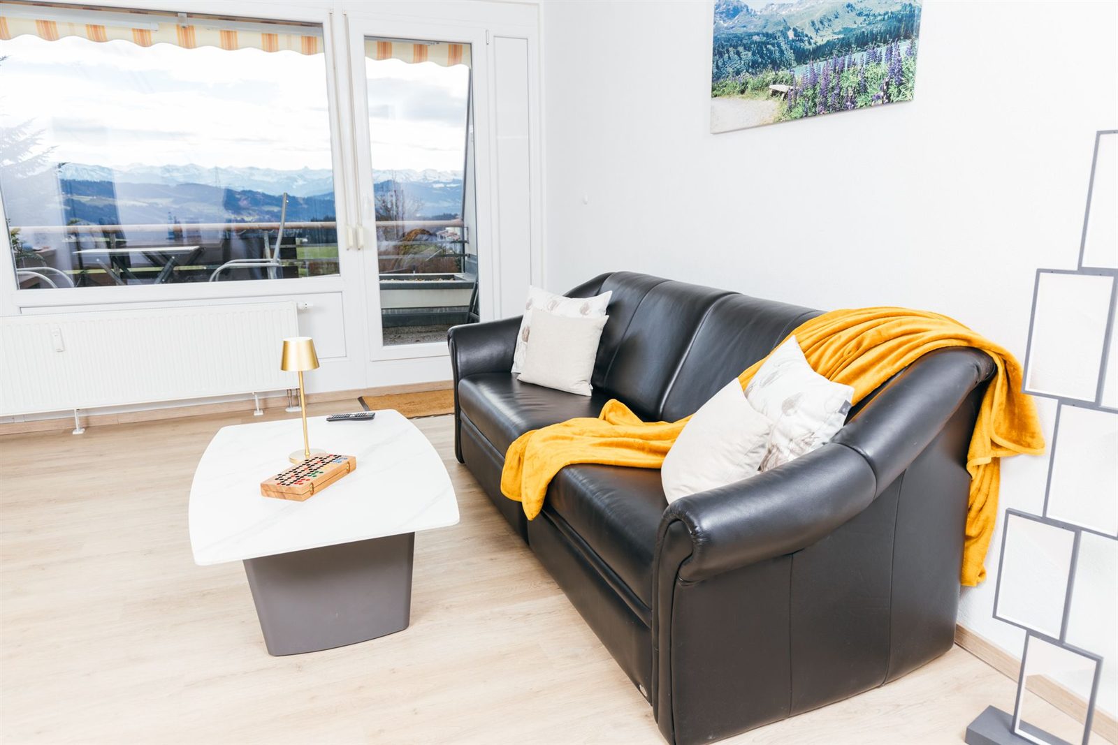 Wohnzimmer · Das Ledersofa lässt sich zum Bett ausklappen, dahinter der Blick auf die Alpen